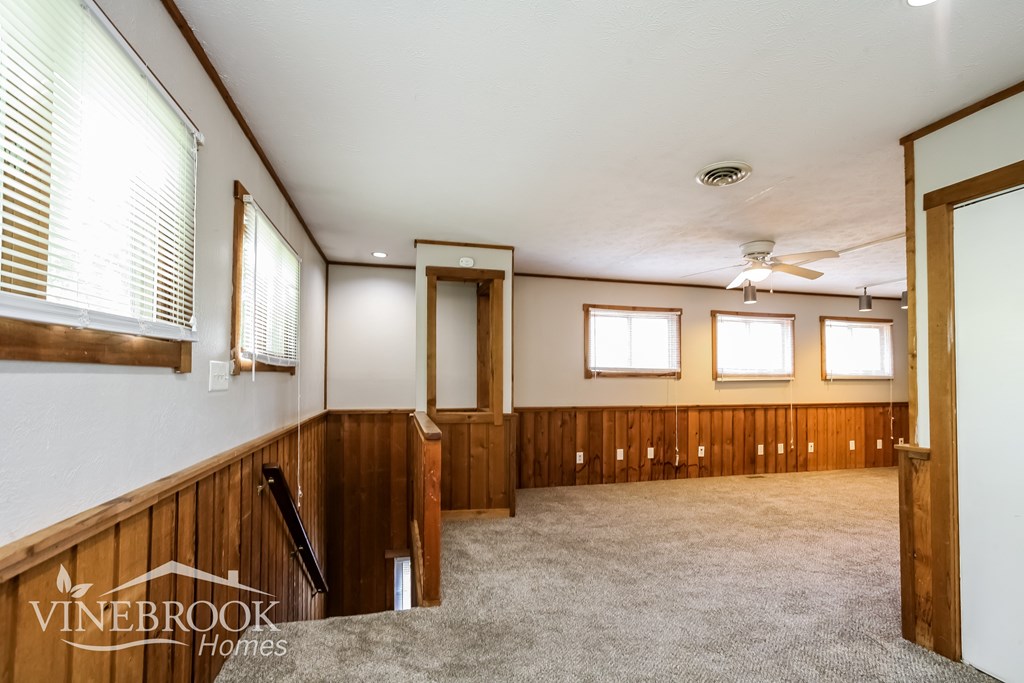 A room with a carpet floor and a ceiling fan.