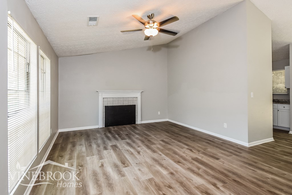an empty living room with a fireplace and a ceiling fan