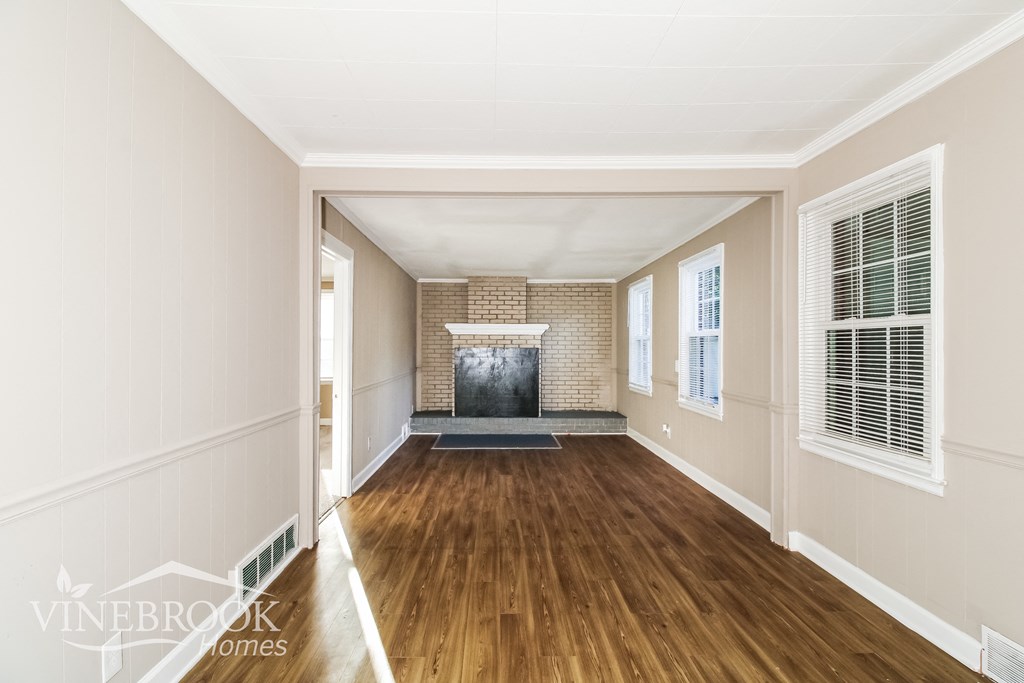 a view of a living room with wood floors and a fireplace