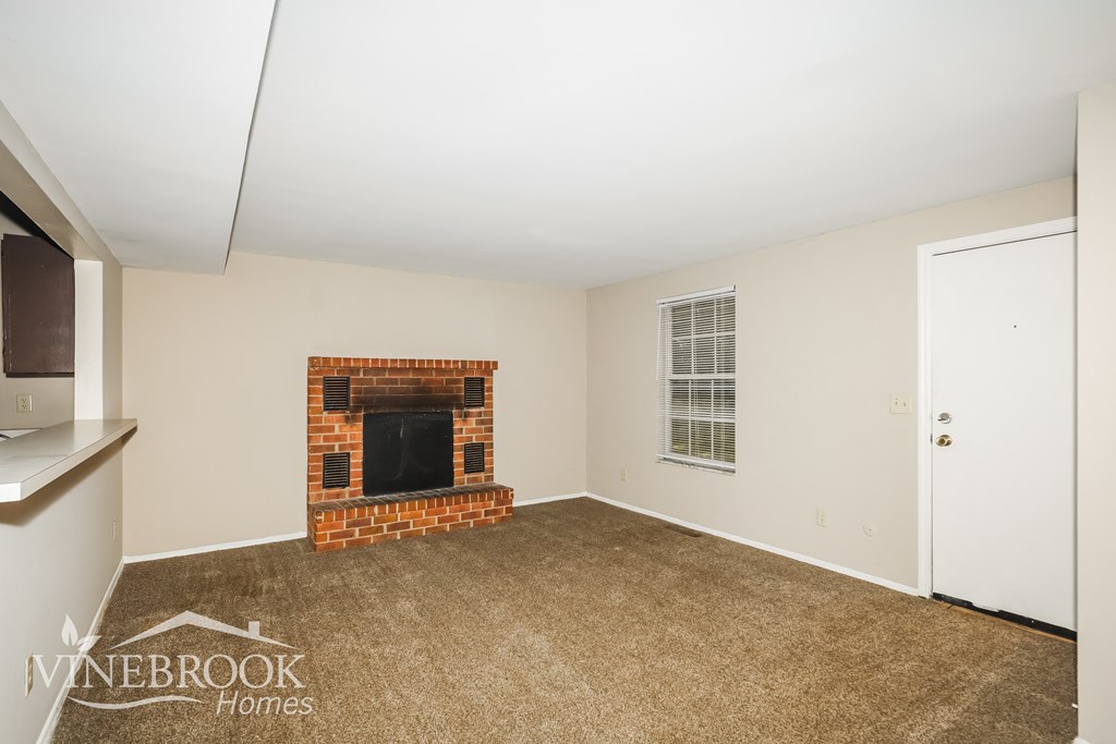 a living room with a fireplace and a carpeted floor