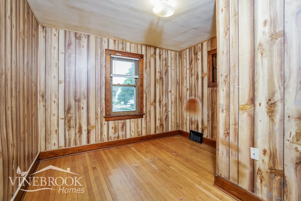 a wood paneled room with wood floors and a window
