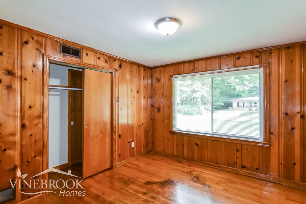 a bedroom with wood paneling and a window and a door