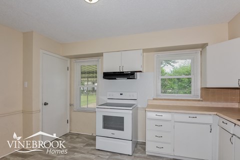 A kitchen with white appliances and cabinets is shown.
