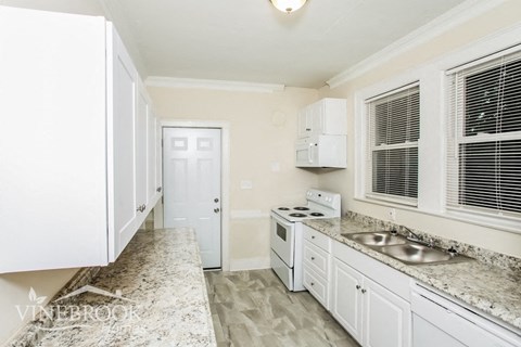 A kitchen with white cabinets and a marble countertop.