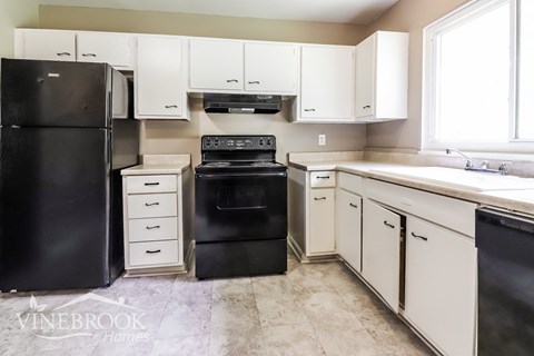 A kitchen with black and white appliances and cabinets.