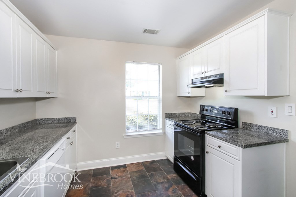 a kitchen with white cabinets and black appliances and a window