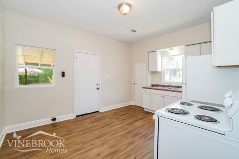 A white stove is in a kitchen with wood floors and white walls.