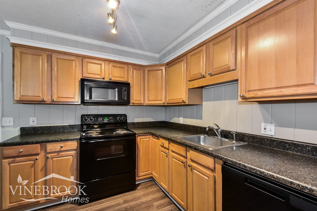a kitchen with wood cabinets and black appliances and granite counter tops