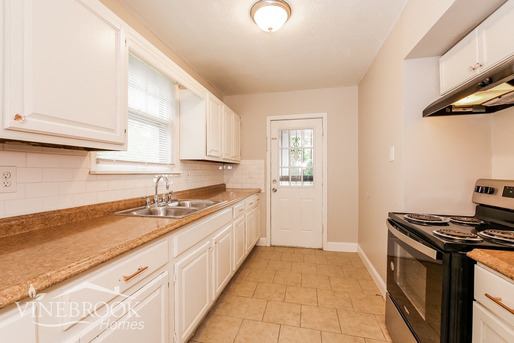 a kitchen with white cabinets and a sink and a stove