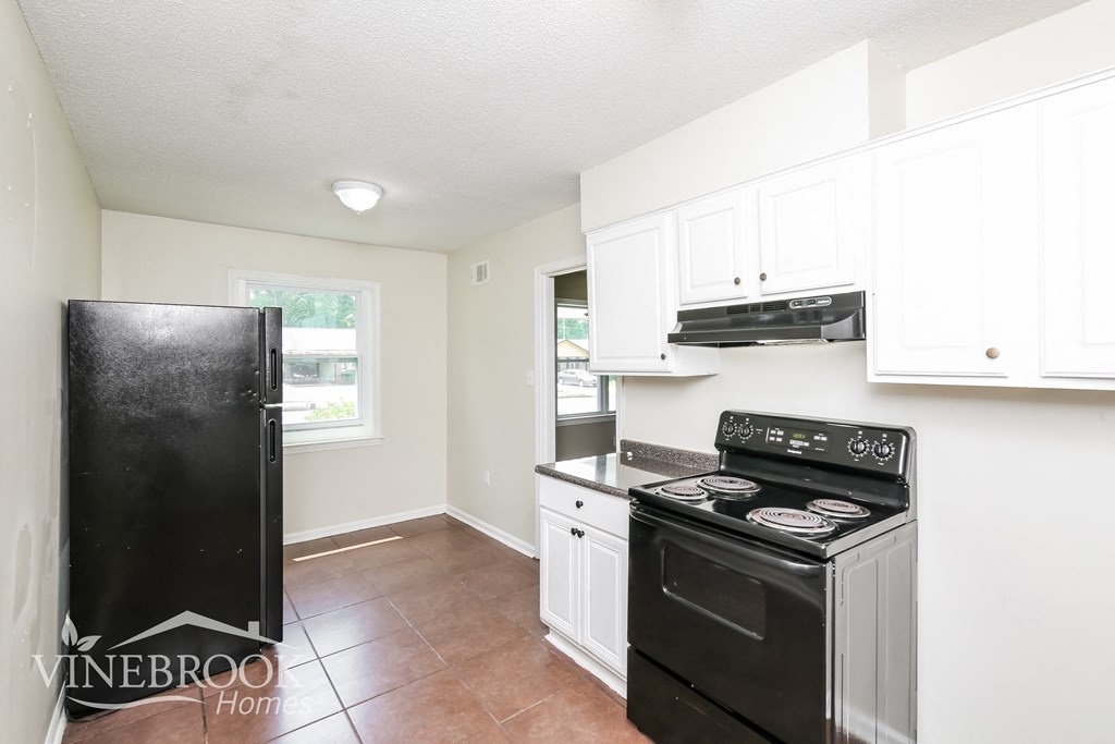 a white kitchen with black appliances and white cabinets