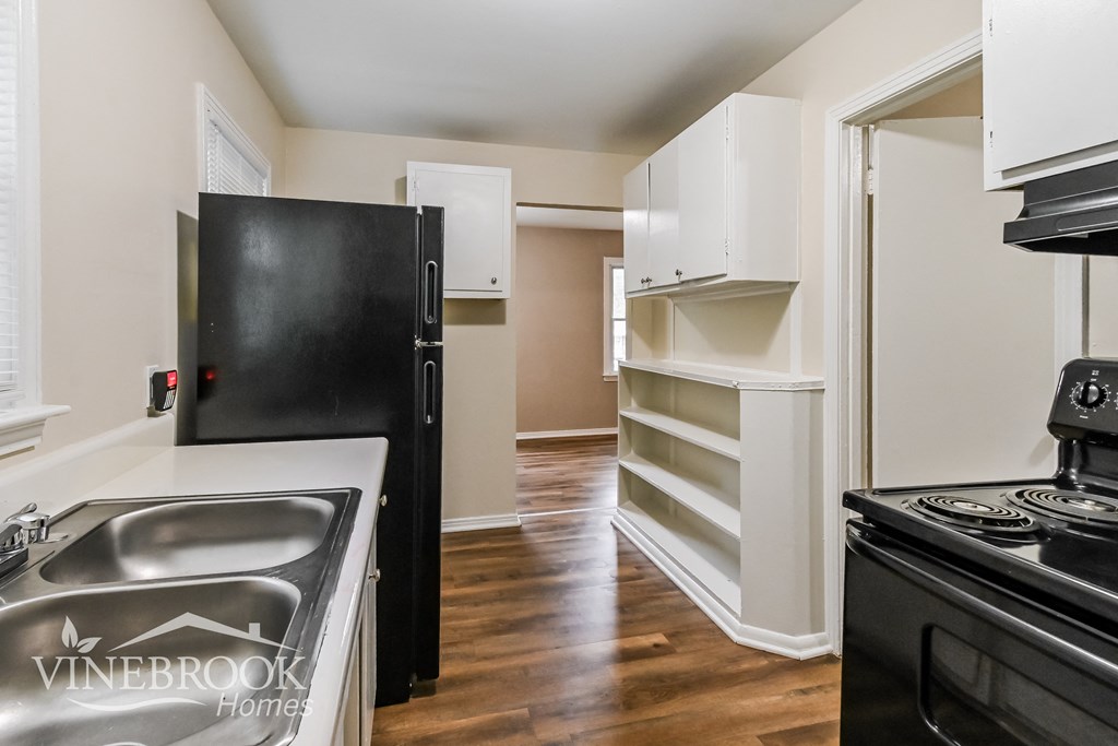 a renovated kitchen with white cabinets and a black stove and refrigerator