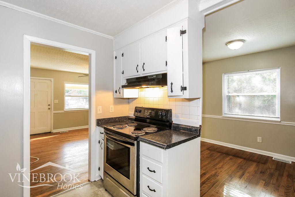 the kitchen of a home with white cabinets and a stove
