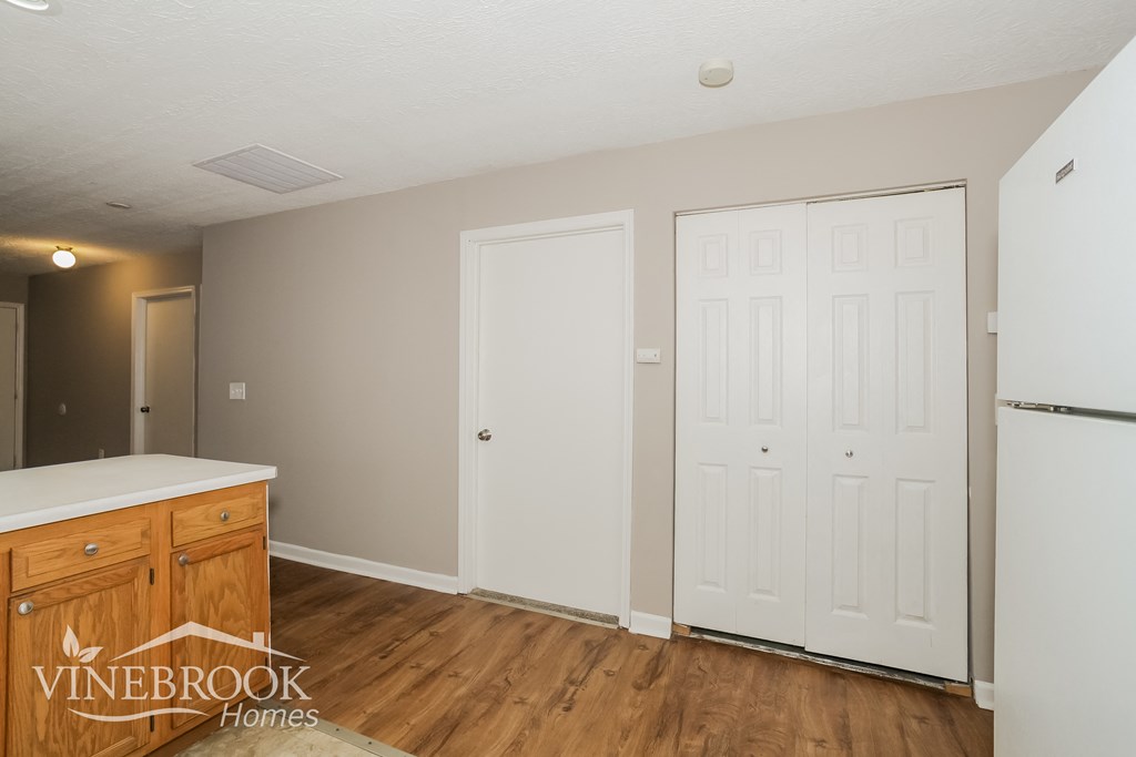 the kitchen and dining room of a house with white doors and a wooden floor