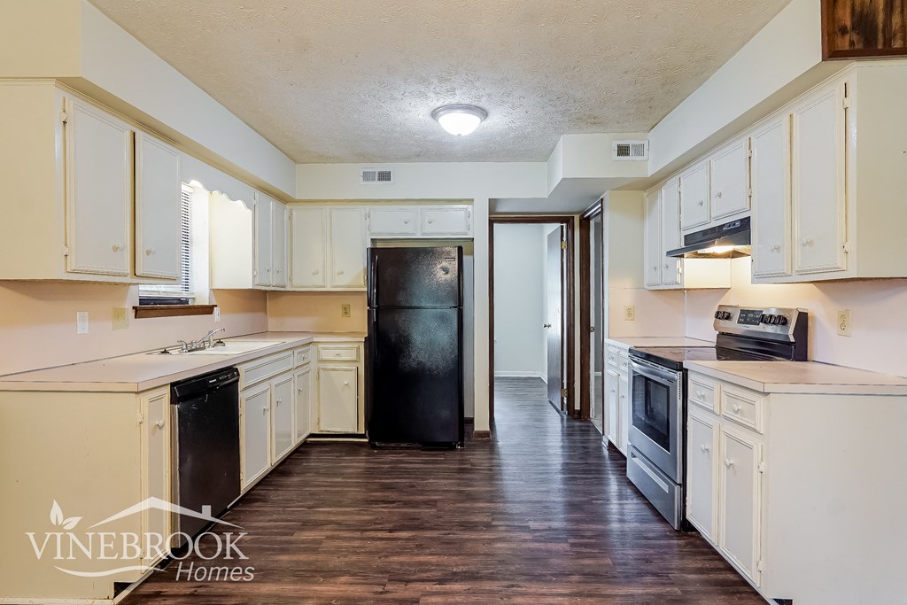 a kitchen with white cabinets and a black refrigerator
