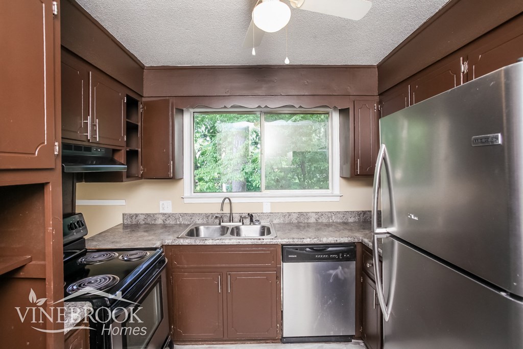a kitchen with brown cabinets and stainless steel appliances and a window