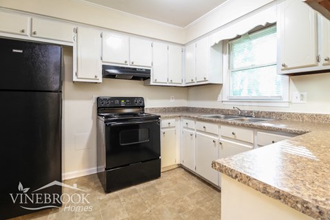 a kitchen with white cabinets and black appliances