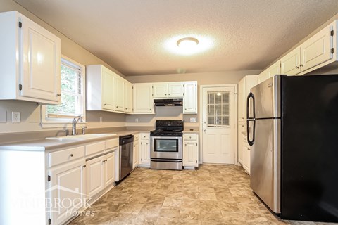 A kitchen with white cabinets and a black refrigerator.