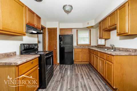 A kitchen with wooden cabinets and a black refrigerator.