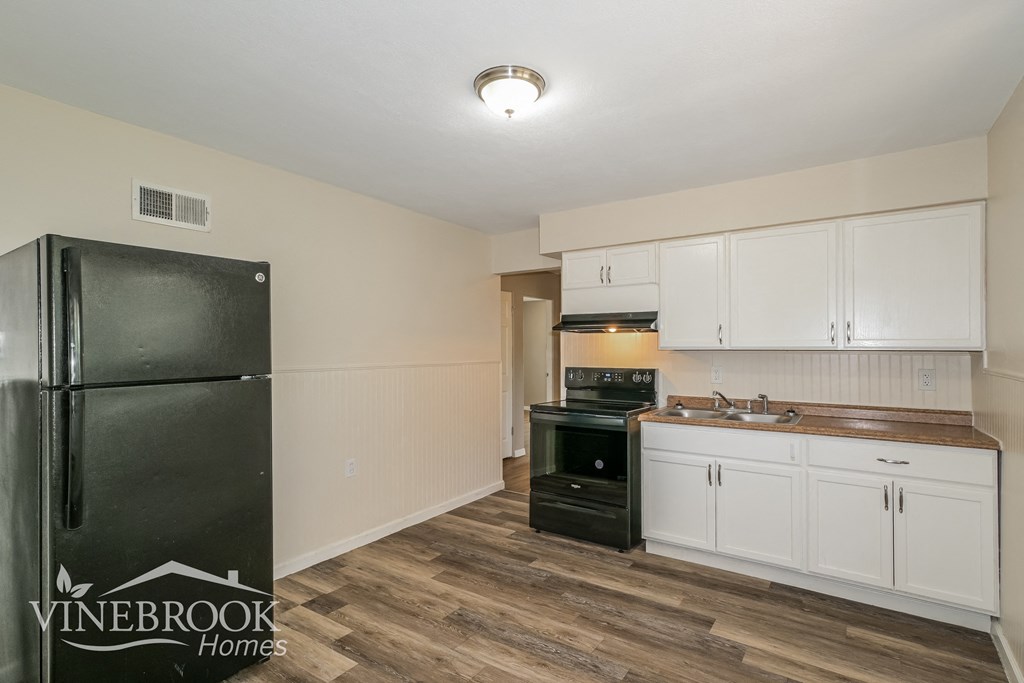 a kitchen with white cabinets and black appliances and a refrigerator