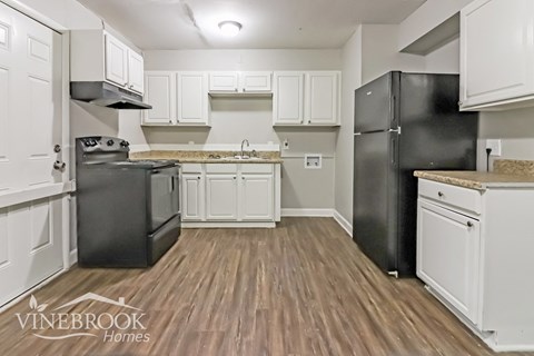 a renovated kitchen with white cabinets and black appliances