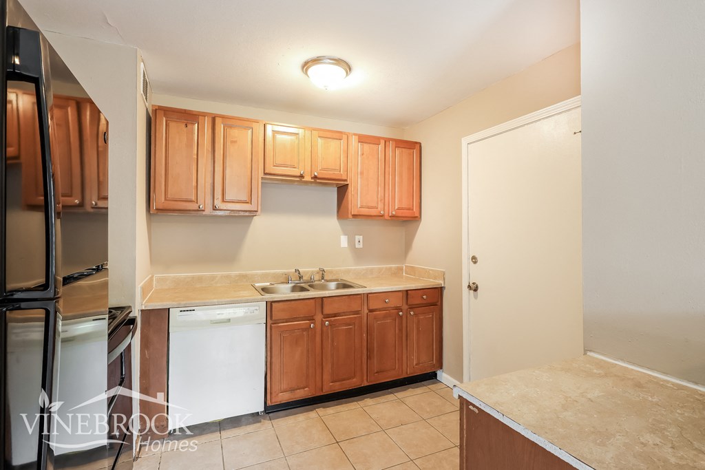 a kitchen with wooden cabinets and a sink and a refrigerator