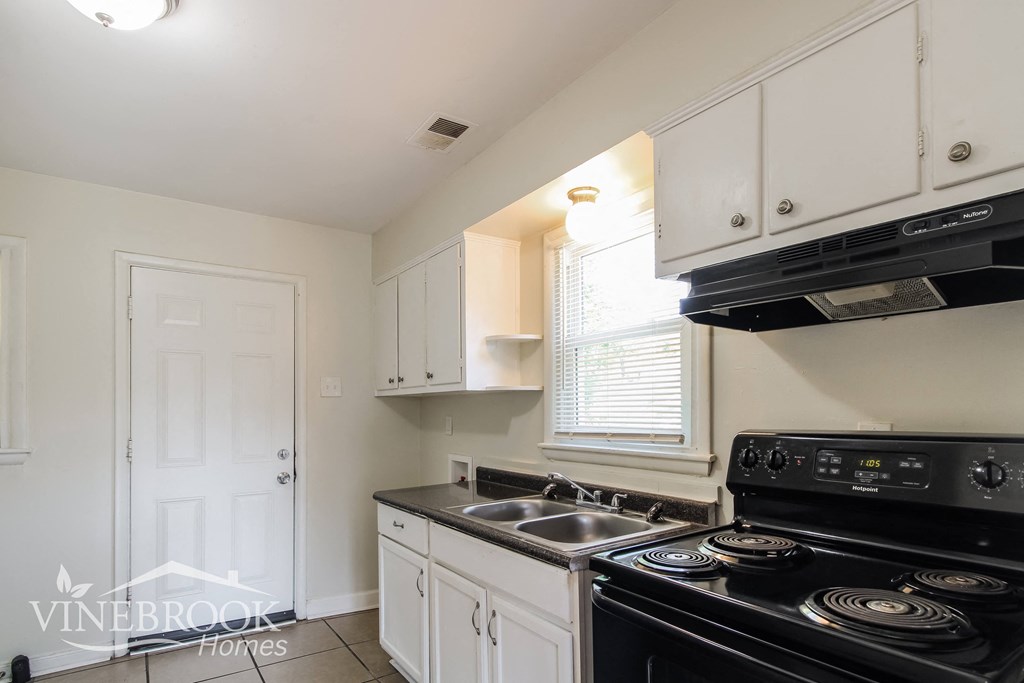 a white kitchen with black appliances and white cabinets