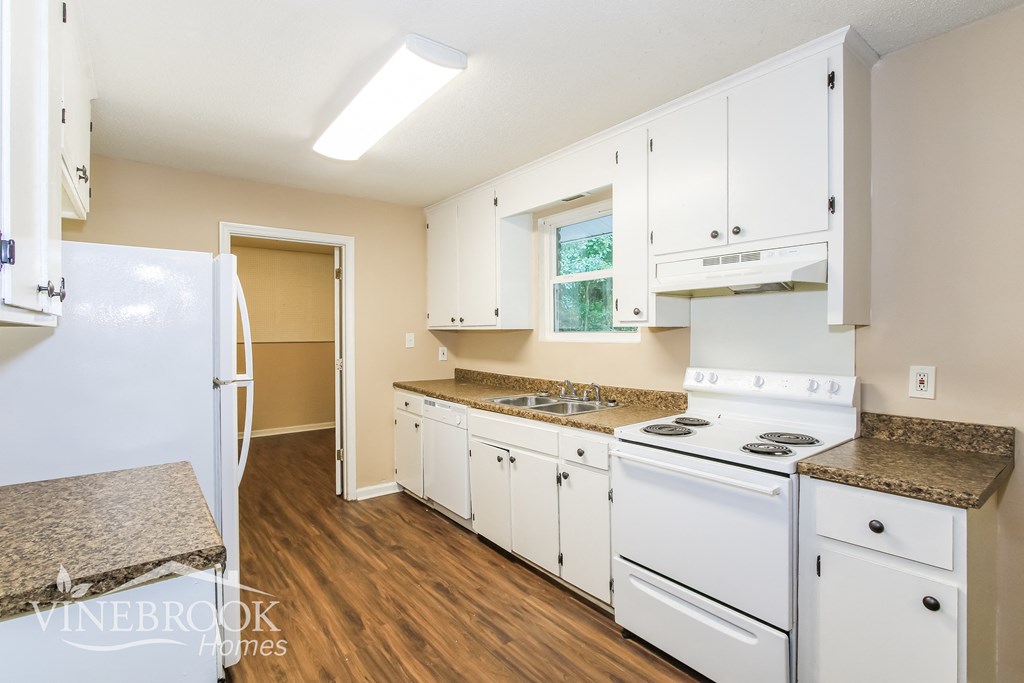 a kitchen with white appliances and white cabinets and wood floors