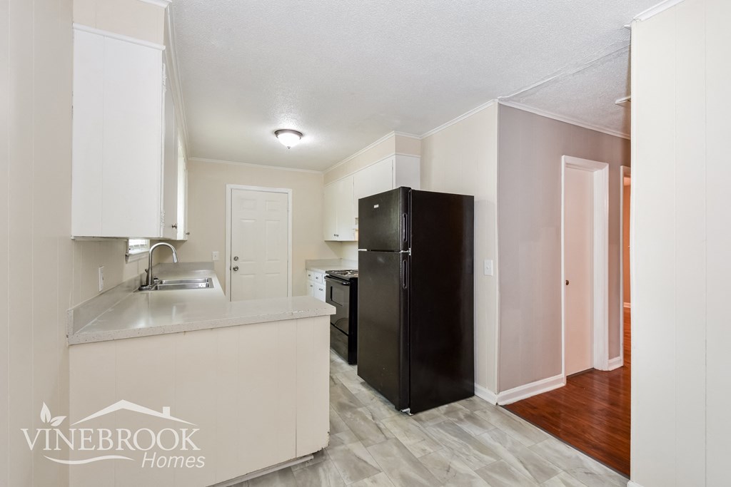 a kitchen with white cabinets and a black refrigerator