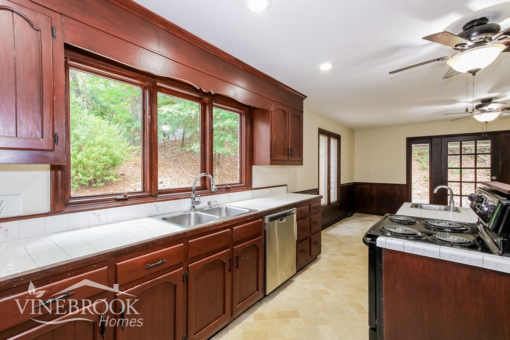 a kitchen with wood cabinets and a sink and a stove and a window