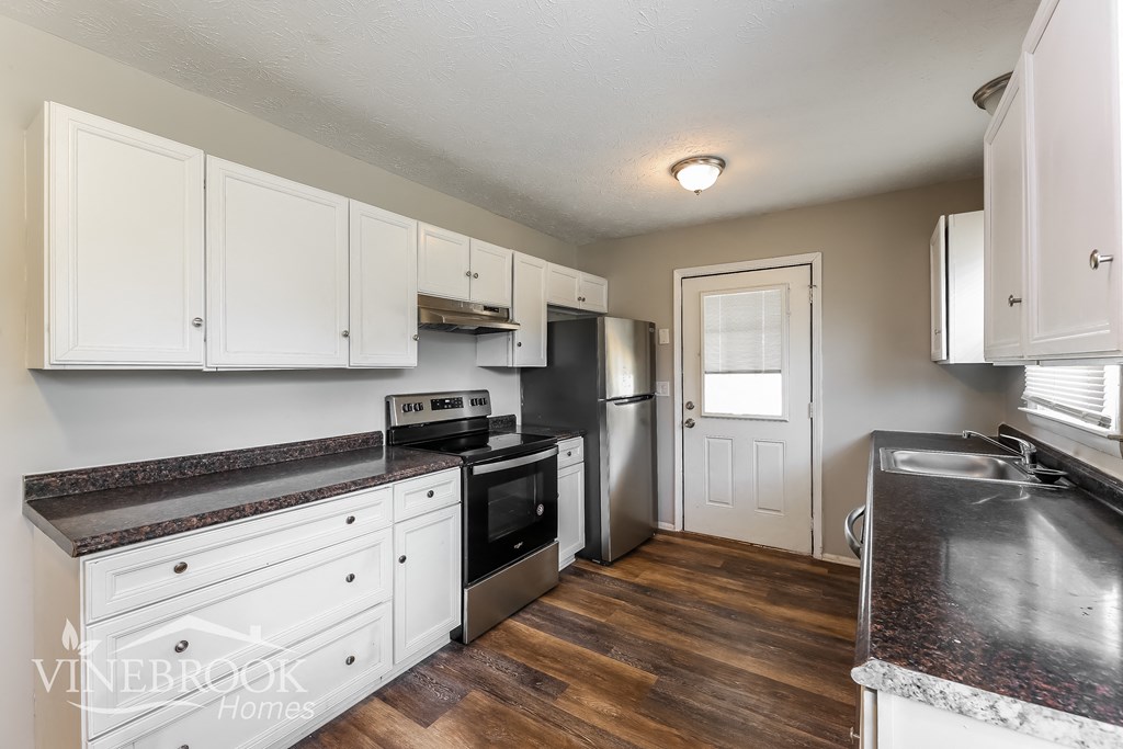 a kitchen with white cabinets and stainless steel appliances and a black stove and refrigerator