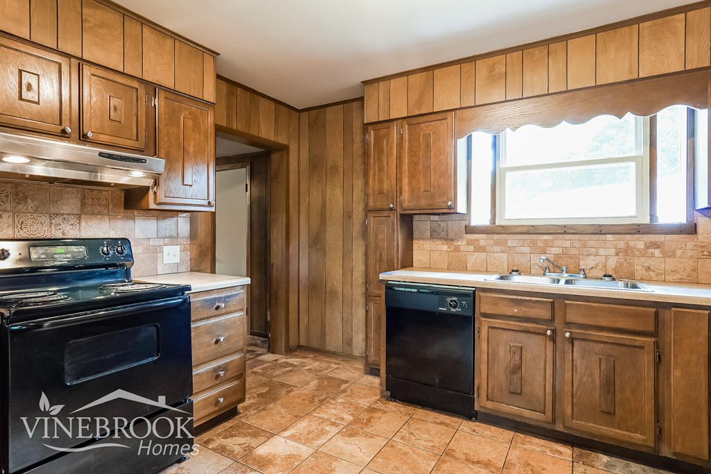 a kitchen with wooden cabinets and a black oven and sink