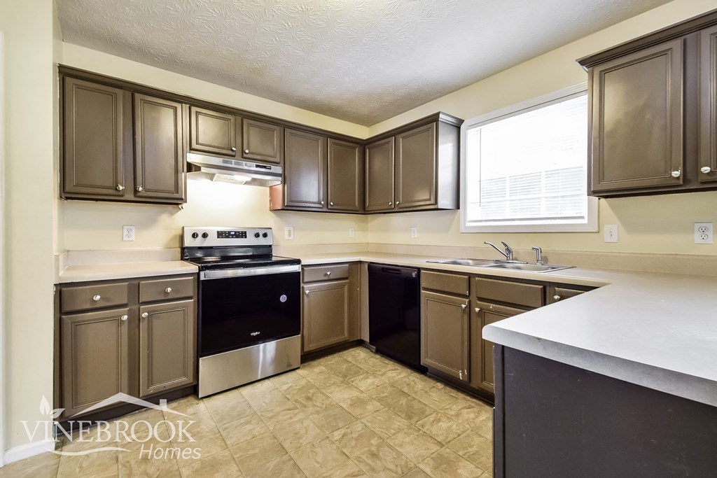 a kitchen with brown cabinets and white counter tops and black appliances