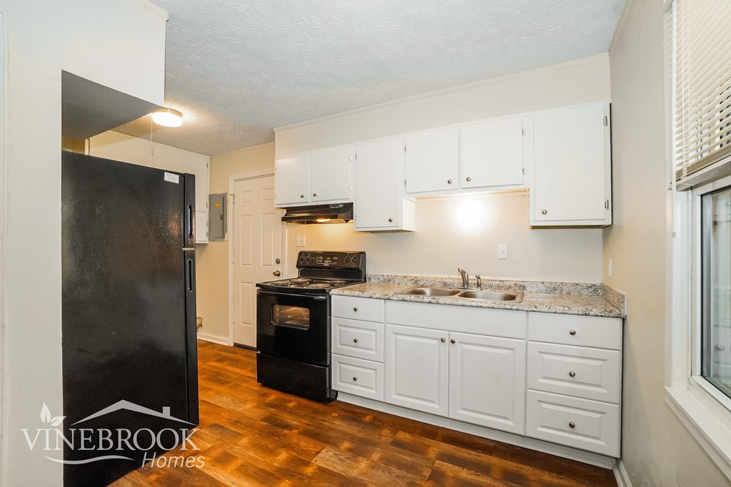 a kitchen with white cabinets and a black stove and refrigerator