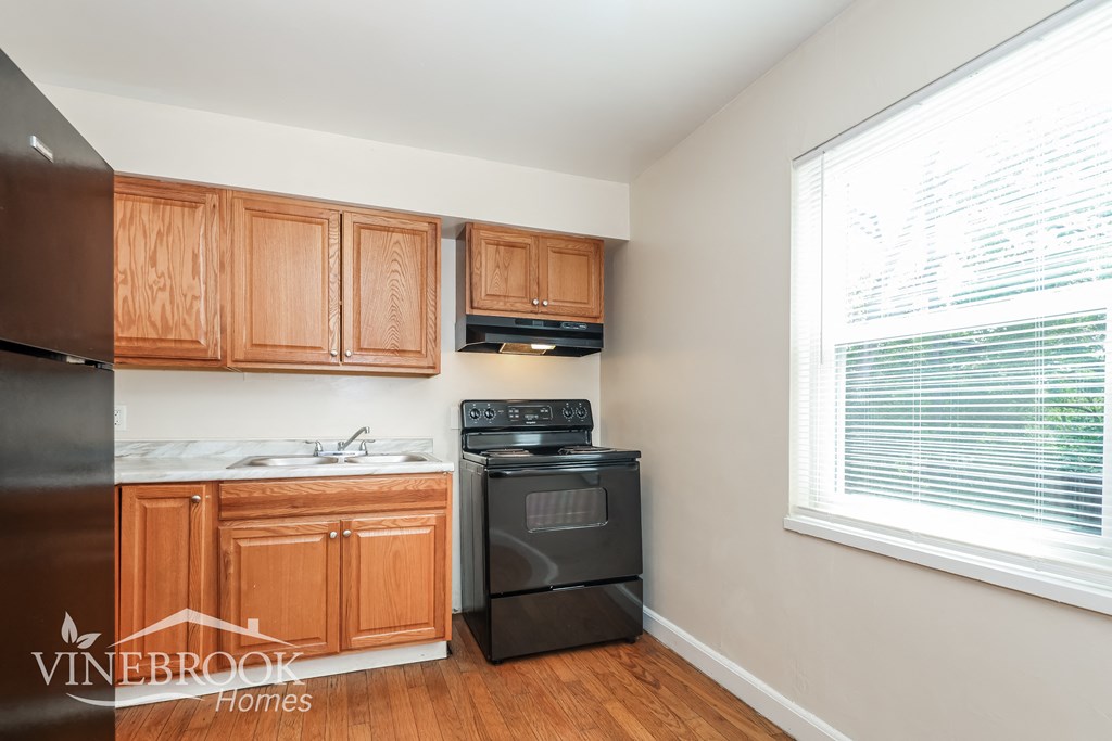 a kitchen with wood cabinets and black appliances and a window