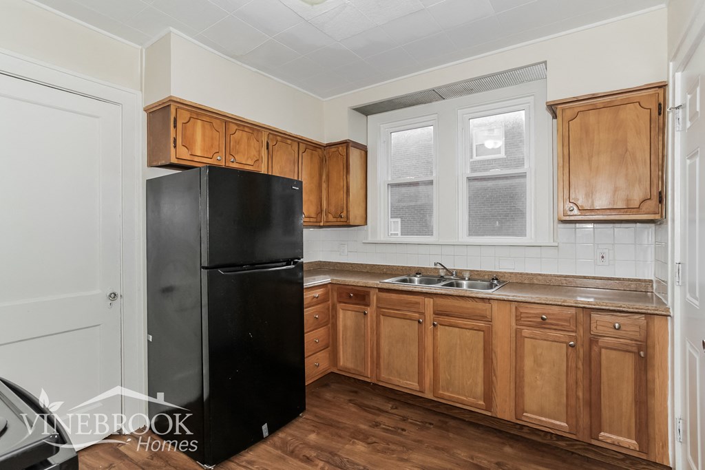 a kitchen with wooden cabinets and a black refrigerator