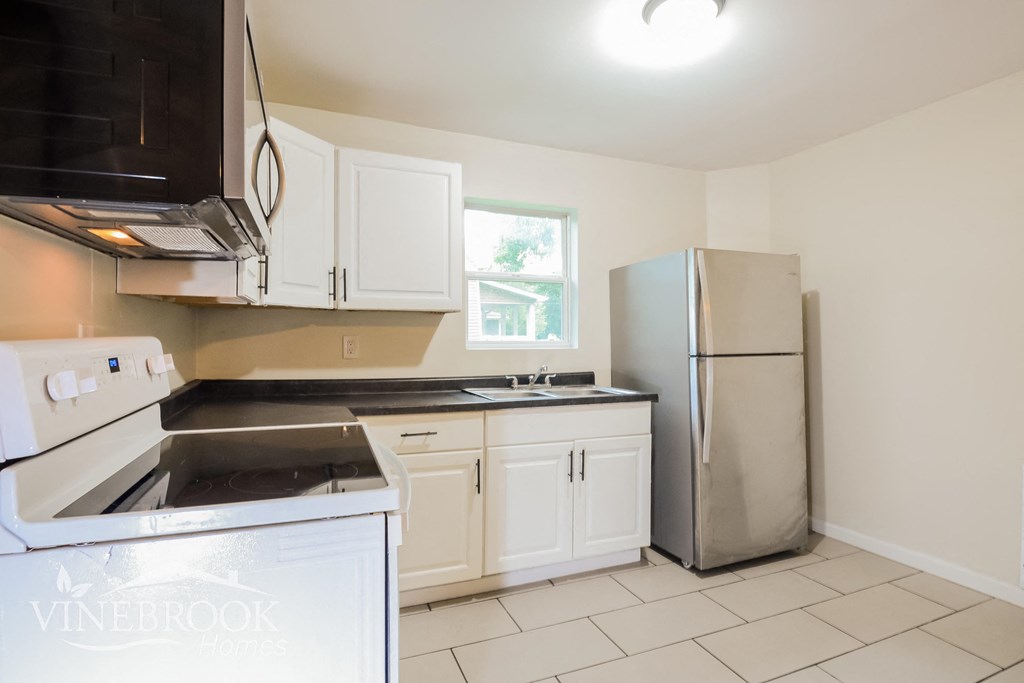 a kitchen with white cabinets and a stainless steel refrigerator