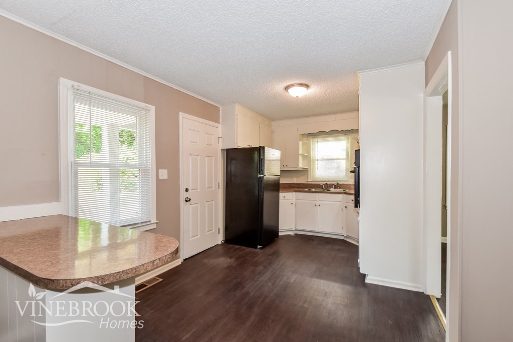 a kitchen with white cabinets and a black refrigerator