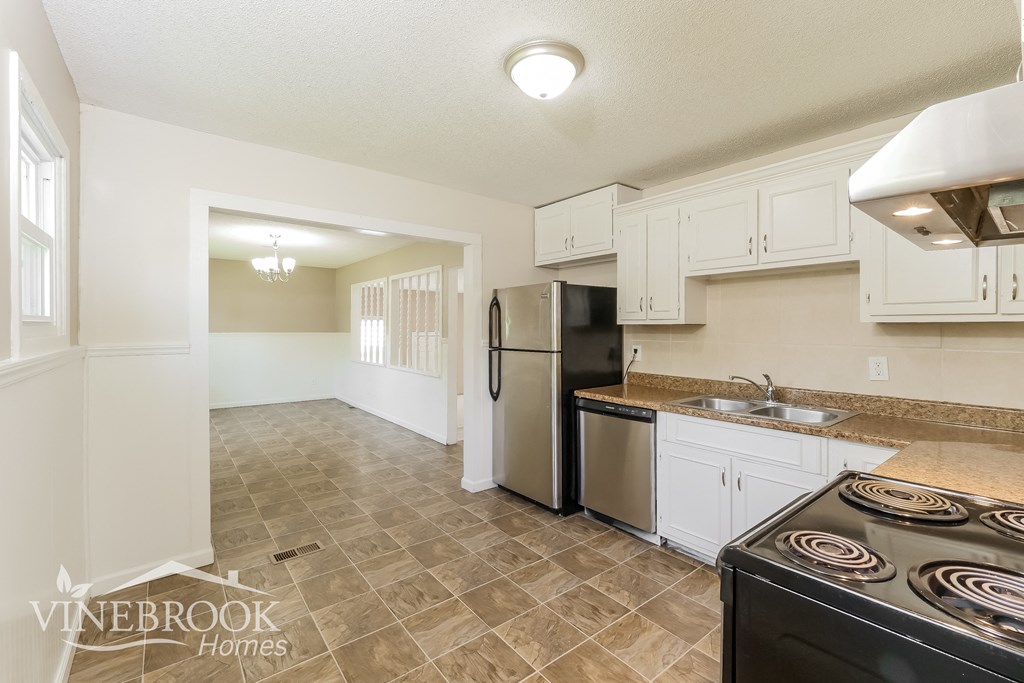 a kitchen with white cabinets and a stove and a refrigerator
