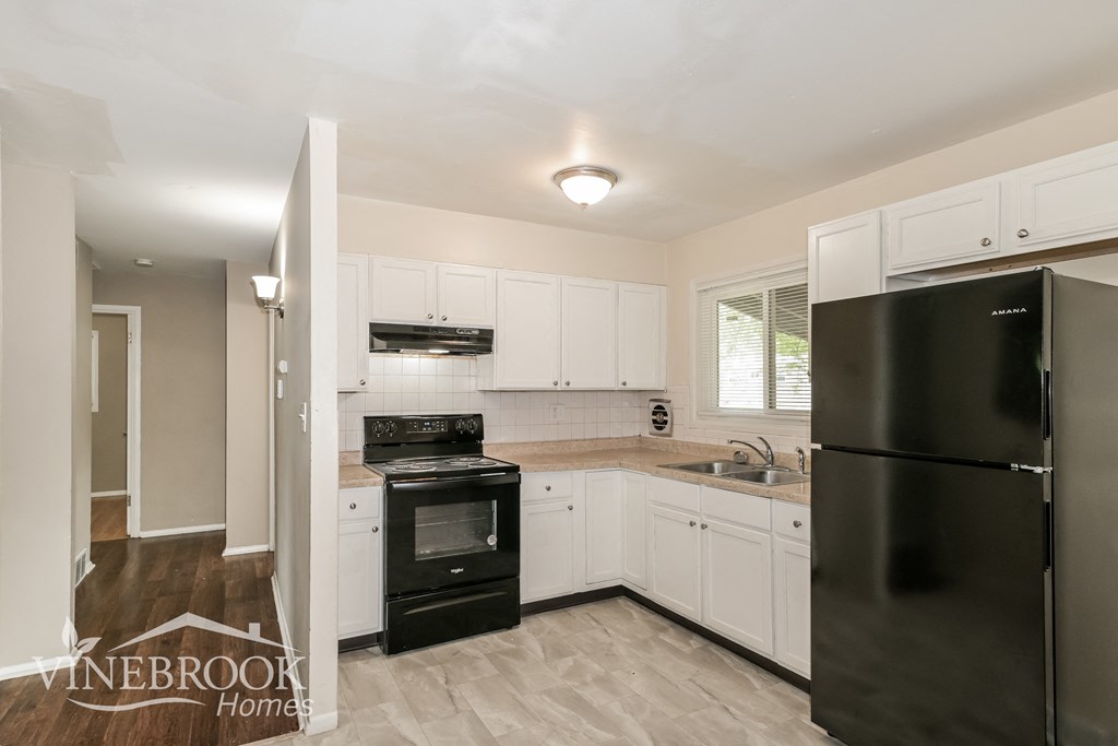 a renovated kitchen with black appliances and white cabinets