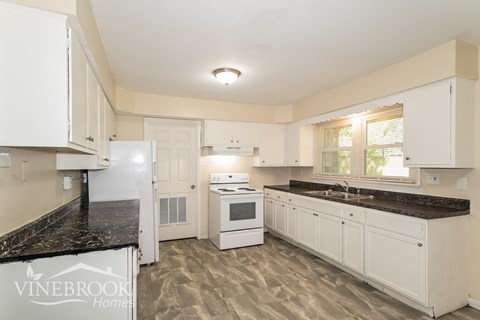 a white kitchen with marble counter tops and white appliances