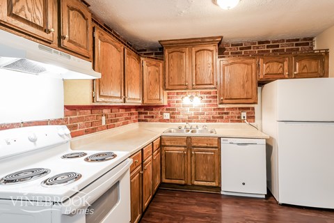 A kitchen with wooden cabinets and a white stove top oven.