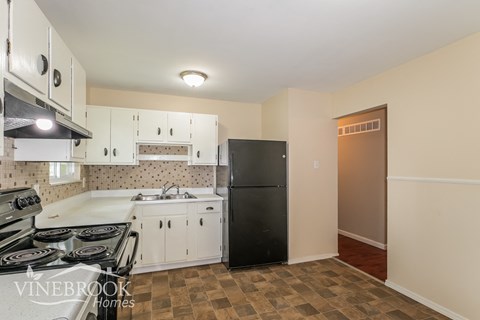 A kitchen with a black refrigerator and white cabinets.
