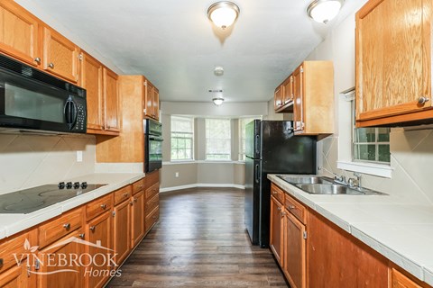 A kitchen with wooden cabinets and a black refrigerator.
