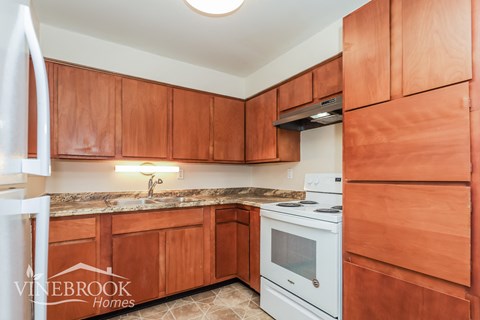 A kitchen with wooden cabinets and a white stove top oven.