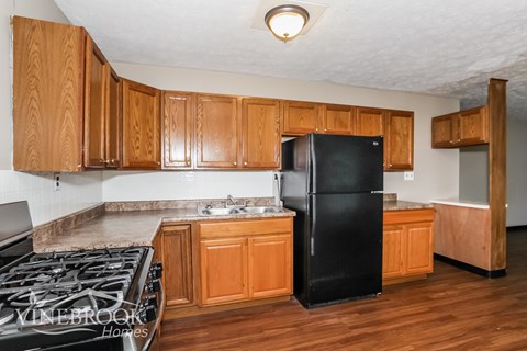 a kitchen with wooden cabinets and a black refrigerator