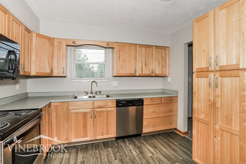 A kitchen with wooden cabinets and a stainless steel dishwasher.