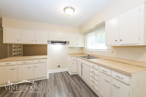 a white kitchen with wood floors and white cabinets