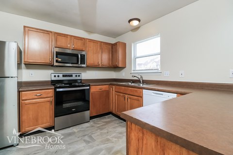 a kitchen with wooden cabinets and stainless steel appliances and a marble counter top
