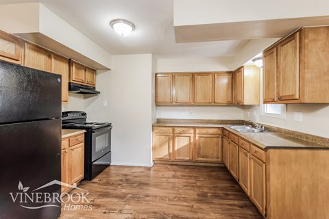 A kitchen with wooden cabinets and a black refrigerator.