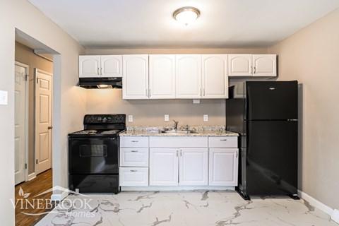 a kitchen with white cabinets and a black stove and refrigerator